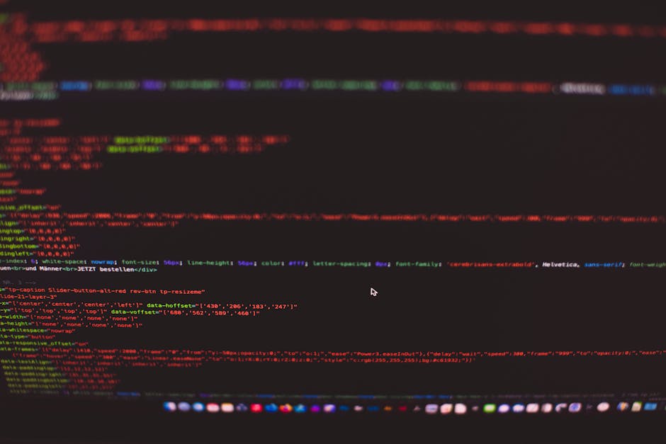 A close-up view of a person's hands typing on a laptop keyboard, with the screen displaying a dark code editor interface filled with lines of programming code in various colors. The laptop is placed o